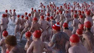 Swimmers enter the water during the annual nude winter solstice swim during Hobart's Dark Mofo festival at Long Beach in Sandy Bay, Tasmania, Wednesday, June 22, 2022. (AAP Image/Rob Blakers) NO ARCHIVING
