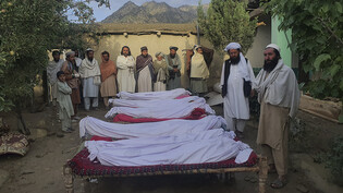 Männer stehen um die sterblichen Überreste von Opfern, die bei einem Erdbeben im Dorf Gayan in der afghanischen Provinz Paktika getötet wurden. Nach dem verheerenden Erdbeben in der afghanisch-pakistanischen Grenzregion hat Regen die Rettungsarbeiten…
