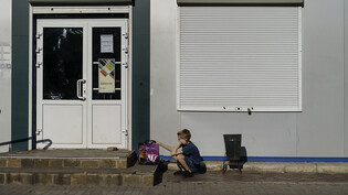 Ein Kind wartet auf seine Mutter vor einem der wenigen noch geöffneten Geschäfte in der Stadt Slowjansk. Foto: David Goldman/AP/dpa