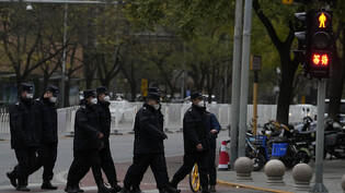 Chinesische Sicherheitskräfte gehen in Peking an einer Kreuzung in der Nähe des Ortes der Proteste vom Vortag vorbei. Foto: Ng Han Guan/AP/dpa