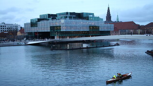 Ein Ruderboot fährt an der Brücke Lille Langebro und am Blox vorbei, einem Gebäude in Kopenhagen, in dem sich auch das Dänische Architekturzentrum befindet. Foto: Steffen Trumpf/dpa