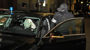 In dunkler Morgenstunde: Ein Polizist steigt während einer Razzia im deutschen Hagen in ein Auto in dem eine festgenommene Person sitzt. Mit einem Grosseinsatz in mehreren Bundesländern ist die Polizei am Mittwoch gegen Mitglieder der italienischen Mafia 'Ndrangheta vorgegangen. 