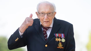 ARCHIV - Der damals 99-jährige Kriegsveteran Tom Moore zeigt seinen Daumen nach oben. Der inzwischen 100 Jahre alte Brite, der mit seinem Spendenlauf am Rollator einen Weltrekord aufgestellt hat, wird zum Ritter geschlagen. Foto: Joe Giddens/PA Wire/dpa