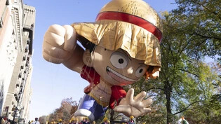 Helfer führen eine Ballon, der aussieht wie «Monkey D. Ruffy» aus der Animeserie One Piece, im Rahmen der traditionellen Thanksgiving-Parade an den Zuschauern auf den Balkonen des Central Park West vorbei. Foto: Jeenah Moon/AP/dpa