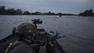 Ukrainische Soldaten fahren mit einem Boot auf dem Fluss Dnipro an der Frontlinie in der Nähe von Cherson. Foto: Felipe Dana/AP/dpa