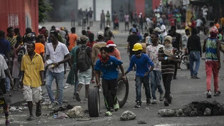 ARCHIV - Während einer Demonstration gegen die Erhöhung der Treibstoffpreise und für den Rücktritt des haitianischen Premierministers Ariel Henry in Port-au-Prince, Haiti, gehen die Menschen mit geplünderten Waren davon. Foto: Odelyn Joseph/AP/dpa