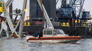 HANDOUT - Auf diesem von der US-Küstenwache zur Verfügung gestellten Foto beobachtet die Besatzung eines Einsatzbootes der Küstenwache der Station Crisfield, wie Abbrucharbeiter den oberen Teil der Nordseite der eingestürzten Francis-Scott-Key-Brücke in…