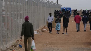 ARCHIV - Personen gehen am Zaun eines Aufnahmezentrums für Migranten in Zypern vorbei. Foto: Petros Karadjias/AP/dpa