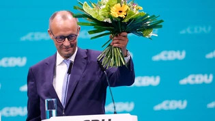 Friedrich Merz, CDU-Bundesvorsitzender, hält seinen Blumenstrauß nach der Wahl zum Bundesvorsitzenden beim CDU-Bundesparteitag hoch. Foto: Carsten Koall/dpa