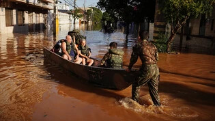 Menschen werden aufgrund der Überschwemmungen durch Mitarbeiter der brasilianischen Streitkräfte mit einem Boot evakuiert. Foto: Carlos Macedo/dpa