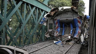 Einer der am Unfall beteiligten Zugwaggons steht auf den Schienen am Unglücksort. Foto: Rodrigo Abd/AP/dpa