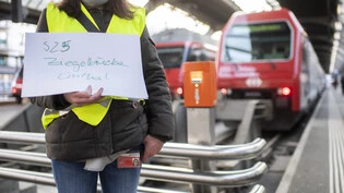 Hier ist der Grund ein Ausfall der Anzeigetafeln in Zürich: Eine Frau zeigt mit einem handgeschriebenen Zettel, wohin der Zug fährt; auch noch provisorisch ist, dass er in ein paar Jahren direkt nur noch bis Ziegelbrücke fährt. 