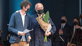 Preisträger hinter der  Maske:  Peter Zumthor (rechts) bedankt sich für Ehre, Blumen und die Laudatio von Men Duri Arquint.
