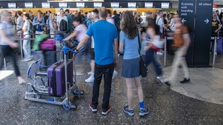 Dichtestress auf dem Weg in die Ferien: Am Flughafen Zürich warten Reisende vor einem Check-in-Schalter auf die Gepäckabfertigung.